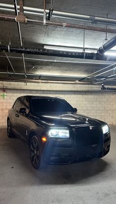 a black rolls royce parked in a parking garage