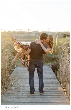 a man holding a woman on top of a wooden walkway