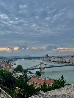 a view of the river and bridge from an overlook point in budapest, with cloudy skies