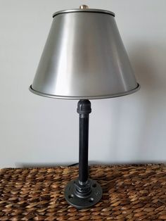 a lamp that is sitting on top of a wicker table cloth with a silver shade