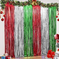 a room decorated for christmas with red, green and silver tinsel curtain backdrops