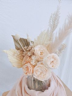 a vase filled with flowers and feathers on top of a table