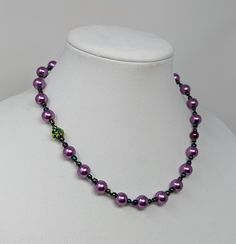 18-inch faux purple pearl necklace with iridescent accents strung on silk cording. Purple Round Beads Pearl Necklace For Gift, Purple Single Strand Pearl Necklace, Purple Pearl Single Strand Necklace, Purple Beaded Pearl Necklace, Purple Pearl Necklaces With Round Beads, Adjustable Purple Pearl Necklace, Adjustable Purple Beaded Pearl Necklace, Adjustable Beaded Purple Pearl Necklace, Adjustable Purple Pearl Necklace With Round Beads