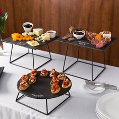 three trays with food on them sitting on a table next to plates and bowls