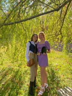 two people standing under a tree in the grass