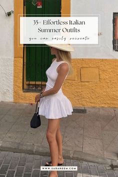 a woman in a white dress and hat standing on the sidewalk