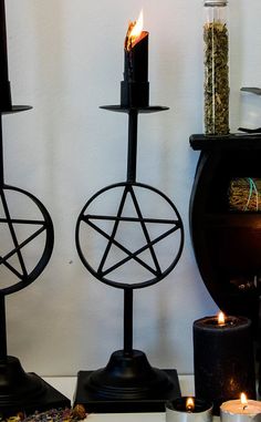 three candles are lit in the shape of pentagrams, with other items around them