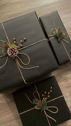 two presents wrapped in black paper and tied with twine, pineconis and evergreen cones