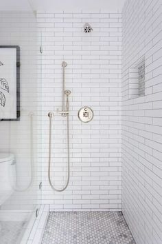 a white tiled bathroom with a walk in shower