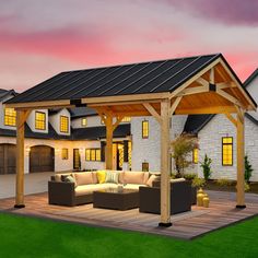 an outdoor living area with couches and tables in front of a house at dusk