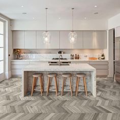 a kitchen with white cabinets and marble counter tops, along with wooden flooring that looks like chevron herrings