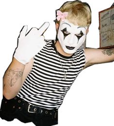 a man with his face painted like a clown holding up a piece of paper in front of him