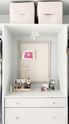 an organized closet with white drawers and clothes hanging on the wall, along with two storage bins