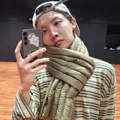 a young man taking a selfie with his cell phone while wearing a hat and scarf