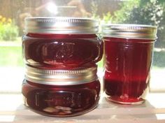 two jars filled with red liquid sitting on top of a window sill