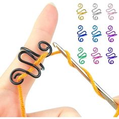 a hand holding a pair of scissors with the word love spelled on it next to several colored crochet hooks