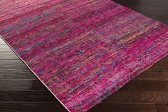 a pink rug with multicolored stripes on the top and bottom, laying on a wooden floor