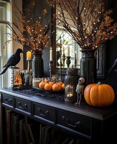 a black table topped with lots of pumpkins and candles in front of a mirror