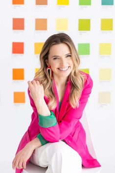 a woman sitting on top of a white chair in front of a wall with color swatches