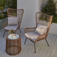 two wicker chairs sitting on top of a wooden deck