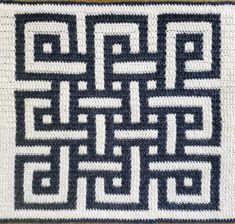 a crocheted rug with black and white squares on it's sides, in the shape of an interlocked square