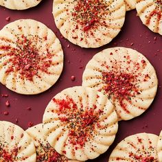 several cookies with sprinkles on them sitting on a purple surface next to each other