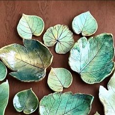 several green leaf shaped dishes sitting on top of a wooden table