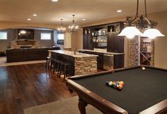 a pool table in the middle of a living room with an entertainment center and bar