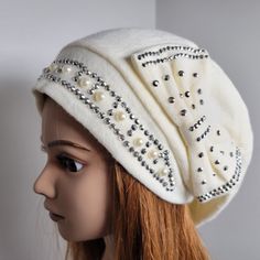 a mannequin head wearing a white hat with pearls and beads on the side