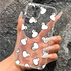 a hand holding up a clear phone case with white ducks on it