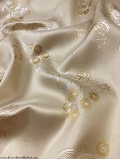 an image of a white and gold fabric with floral design on the bottom half of it