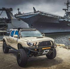 an off - road truck parked in front of a large ship