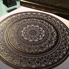 an intricately designed paper with gold foil on it, sitting on top of a table