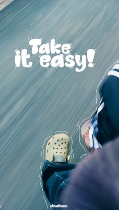 a man riding a skateboard down the side of a road with words take it easy