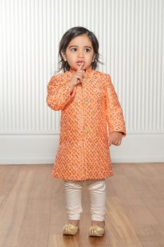 Get your kiddo wedding season ready in this vibrant kids sherwani jacket! Fabric features a metallic pattern throughout and front button closures with a comfortable satin lining. Need it sooner than the estimated delivery? Email us to inquire. Details Spanish Diamond Jacquard Satin Lining Metal Buttons Dry Clean Only Style #103902-22-01 Ethically Produced + Designed in NYC Kurta And Sneakers, Festive Orange Sherwani For Eid, Festive Orange Sherwani With Zari Work, Orange Sherwani For Eid Festivities, Orange Festive Sherwani For Diwali, Orange Sherwani For Diwali Festive Occasion, Gold Embroidered Chanderi Sherwani, Yellow Fitted Cotton Sherwani, Kids Sherwani