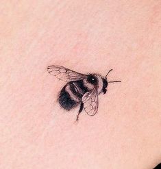 a small tattoo of a bee on the back of a woman's left shoulder