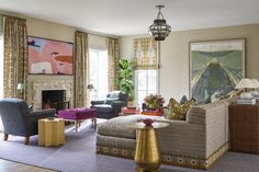 a living room filled with lots of furniture and paintings on the wall next to a fire place