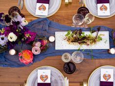 an overhead view of a table with place settings and flowers on the plates, along with wine glasses