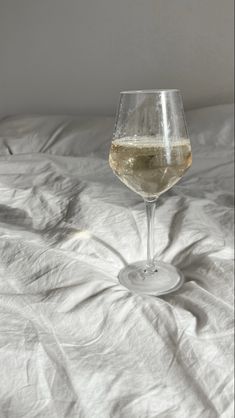 a glass of wine sitting on top of a bed