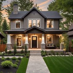 a large house with lots of windows and lights on it's front porch, in the evening