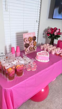 a pink table topped with lots of cakes and desserts