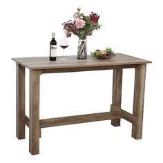 a wooden table topped with a vase of flowers and a bottle of wine