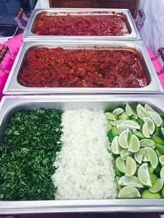 three trays filled with different types of food on top of a pink table cloth