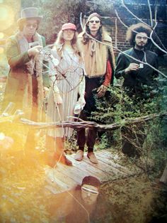 three people standing on a wooden bridge in the woods