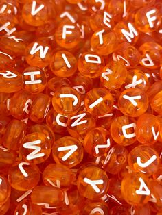 orange beads with white letters and numbers are shown in close up view on the surface