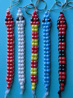 four different colored beads hanging from hooks on a blue surface