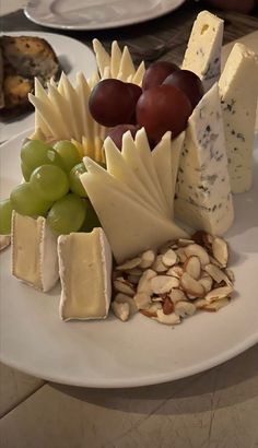 cheese, nuts and grapes are arranged on a plate