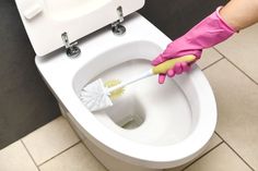 a person in pink gloves is cleaning a toilet with a brush and sponge on it