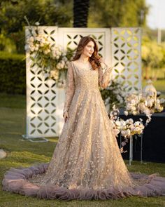 a woman in a long dress standing on the grass