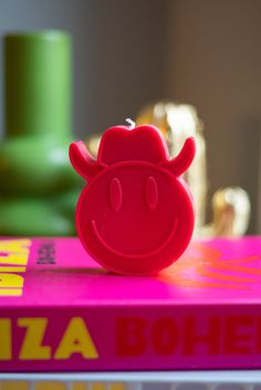 a red toy cow sitting on top of a pink book